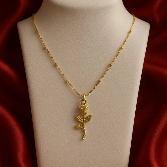 Gold necklace with a rose pendant on a mannequin bust against a red satin background