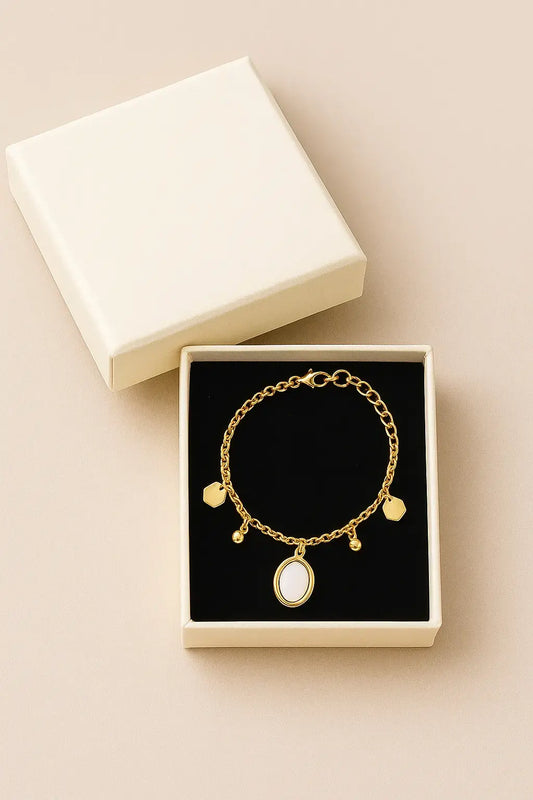 Gold bracelet with charms in a jewelry box on a beige background