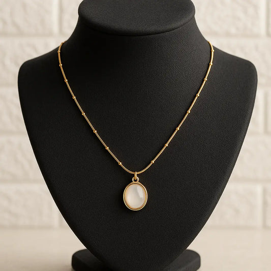 Gold necklace with a pendant on a black mannequin bust against a white background
