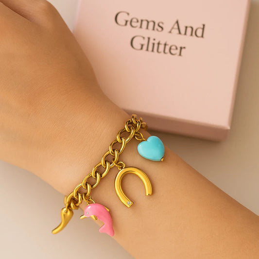 Bracelet with colorful charms on a wrist, with 'Gems And Glitter' box in the background.