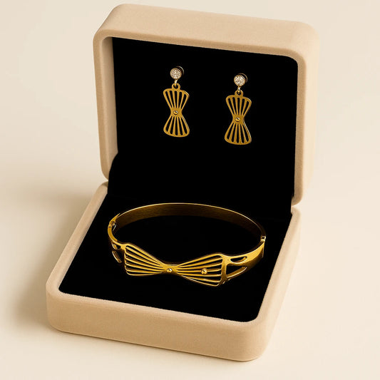 Gold bracelet and earrings set in an open jewelry box on a beige background