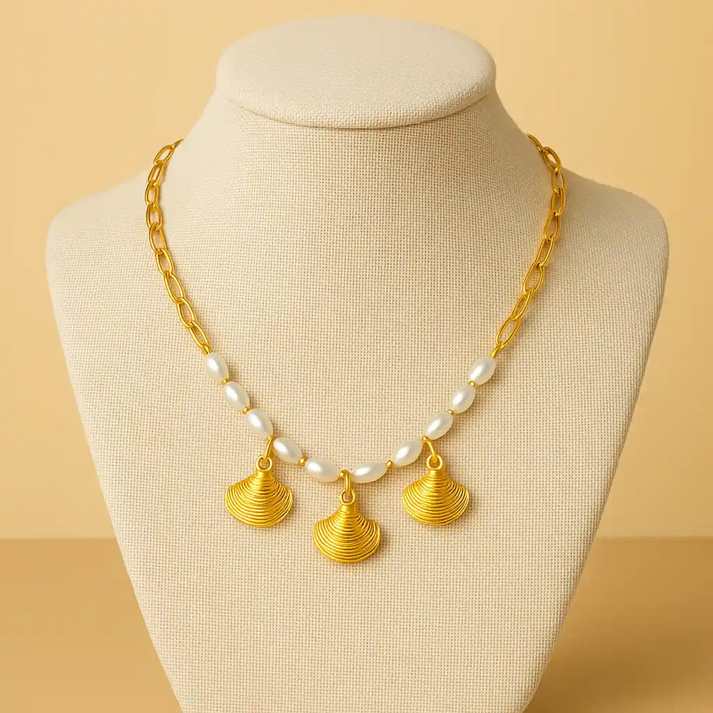 Gold necklace with shell-shaped pendants on a mannequin bust against a beige background