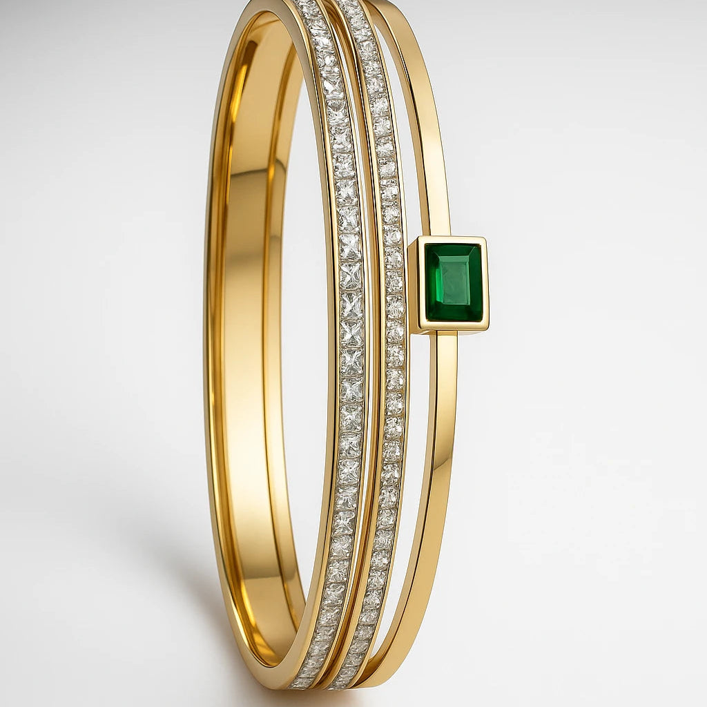 Gold bracelet with emerald and diamonds on a light gray background