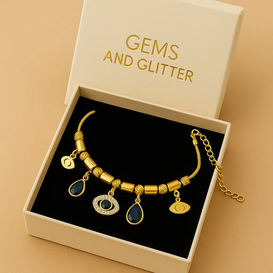 Gold bracelet with gemstones in a box labeled 'Gems and Glitter' on a beige background