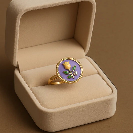 Gold ring with a purple stone and floral design in a beige jewelry box.