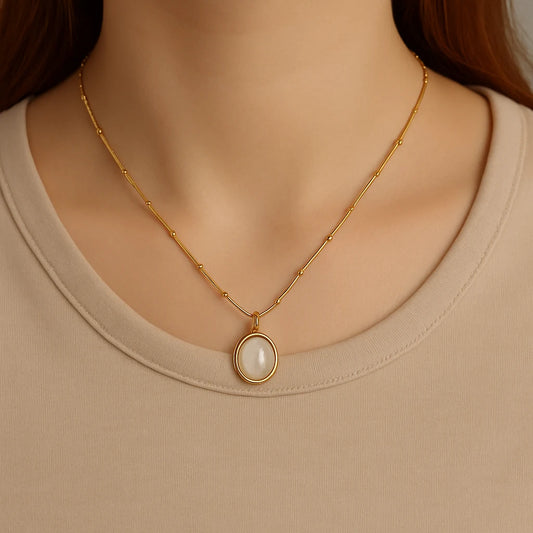 Gold necklace with a pearl pendant on a beige background