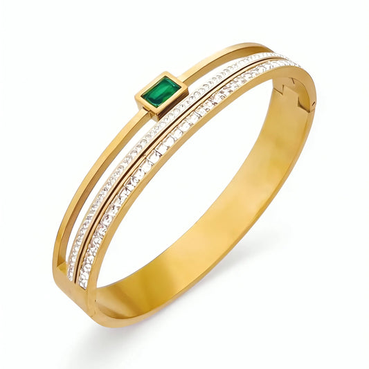 Gold bracelet with a green gemstone and clear stones on a white background