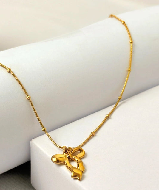 Gold necklace with a bow pendant on a white surface