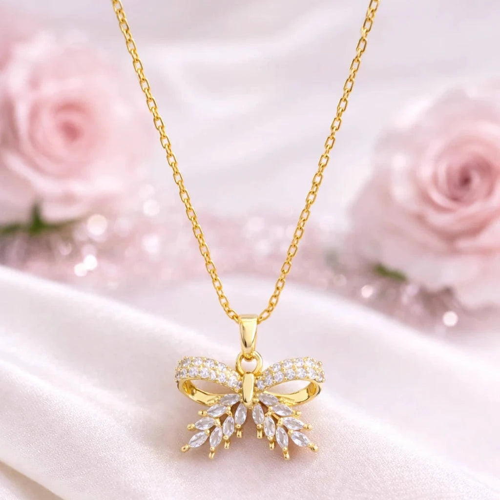 Gold butterfly necklace with diamonds on a white satin background with pink roses.