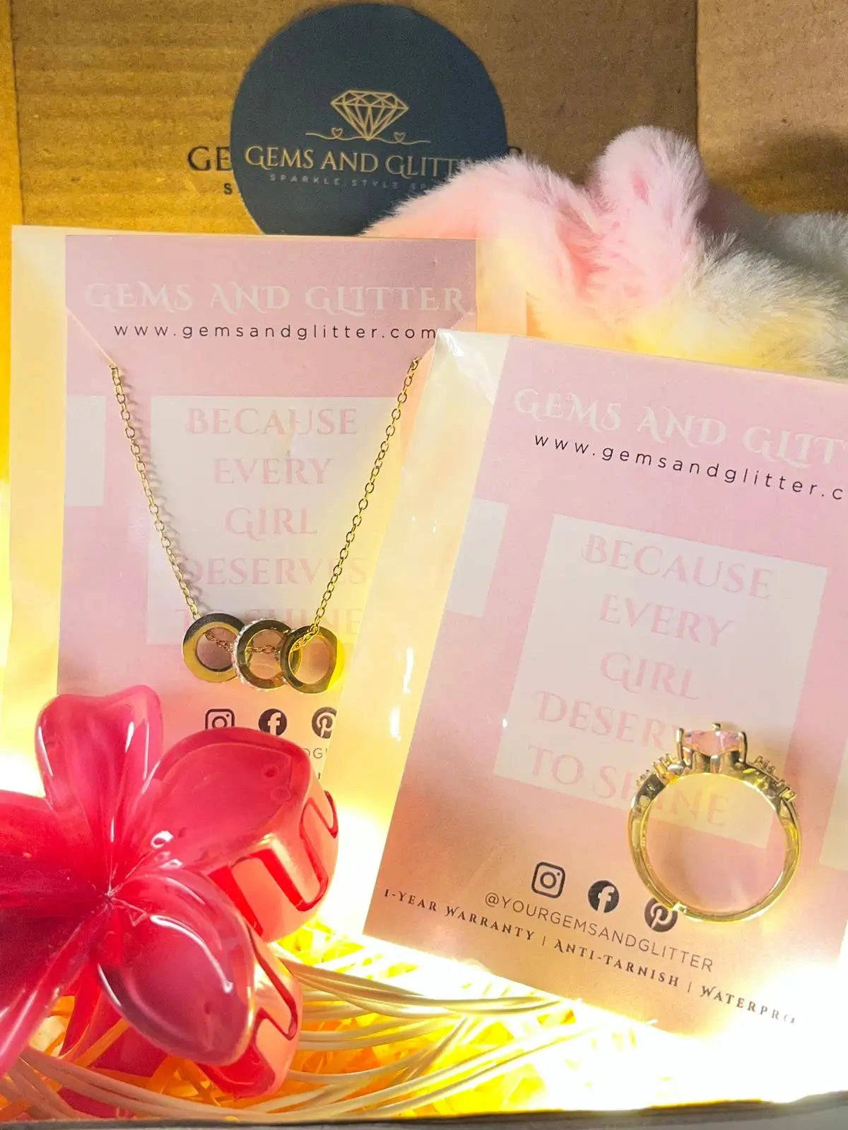 Necklace with heart pendants on a 'Gems and Glitter' card with a pink flower and yellow box in the background.