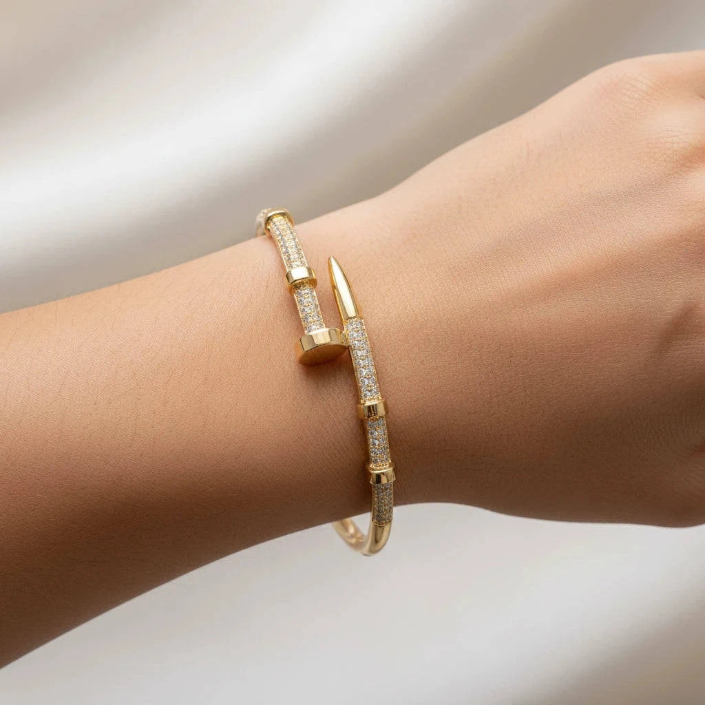 Gold bracelet with clear stones on a wrist against a neutral background