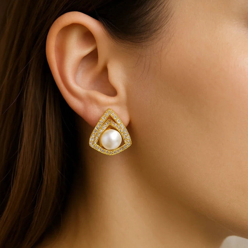 Gold earrings with a pearl on an ear, close-up shot.