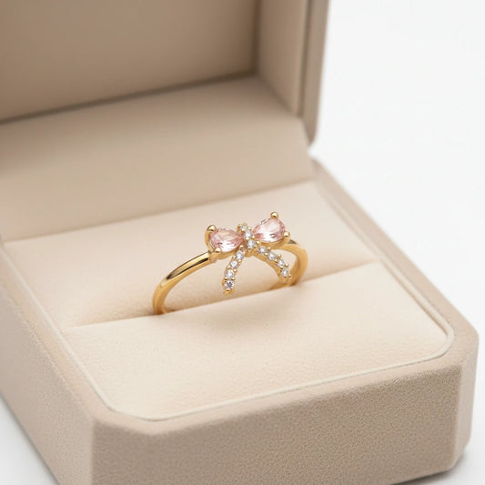Gold ring with pink gemstones in a beige jewelry box