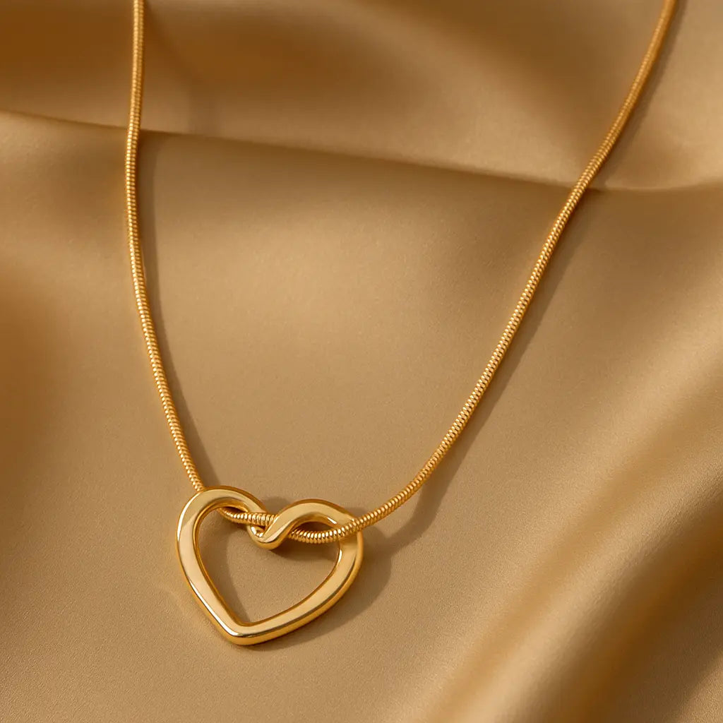 Gold necklace with a heart-shaped pendant on a beige fabric background