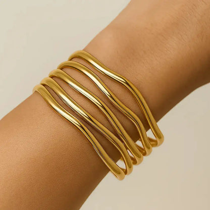 Gold bracelet on a wrist against a beige background