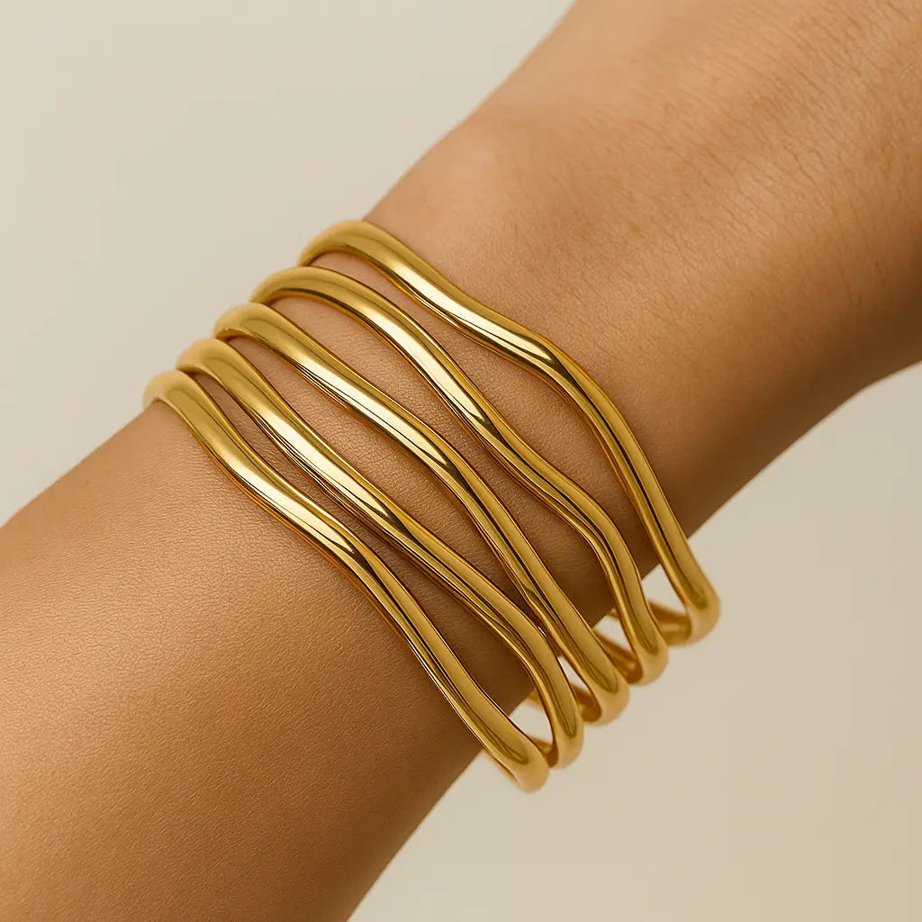 Gold bracelet on a wrist against a beige background