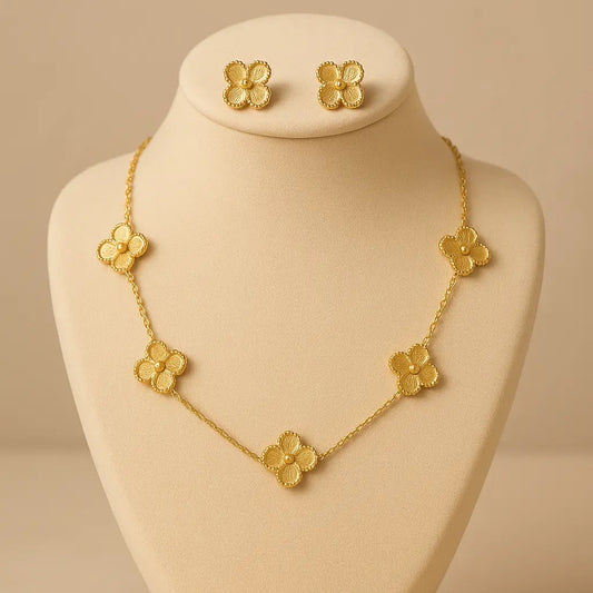 Gold necklace and earrings on a beige mannequin bust against a beige background