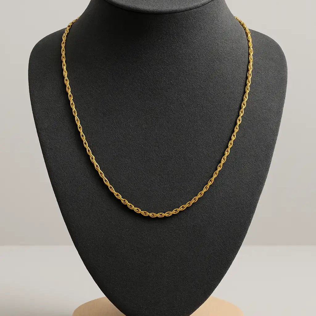Gold chain necklace on a black mannequin bust with a gray background