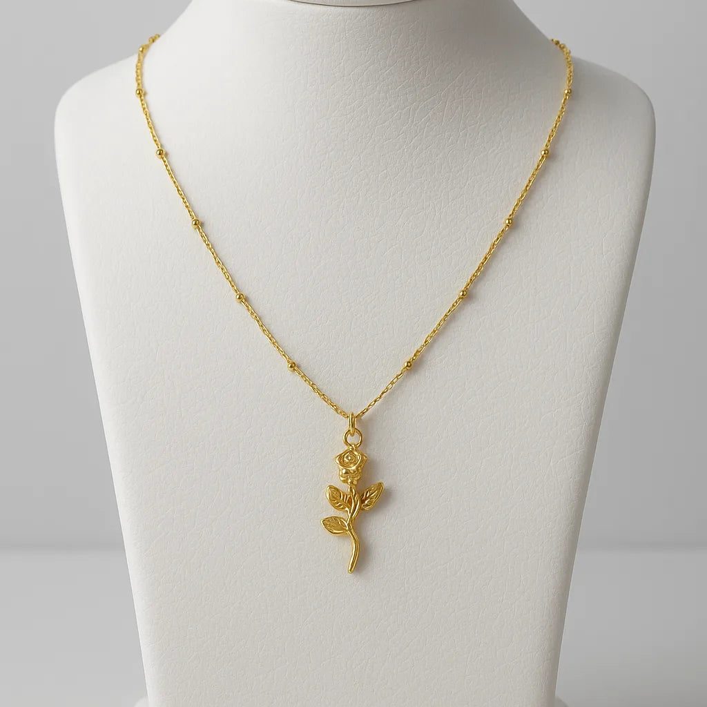 Gold necklace with a leaf pendant on a mannequin bust against a gray background