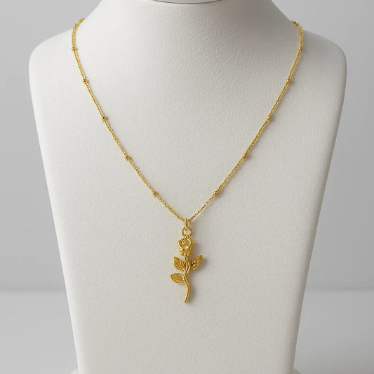 Gold necklace with a leaf pendant on a mannequin bust against a gray background