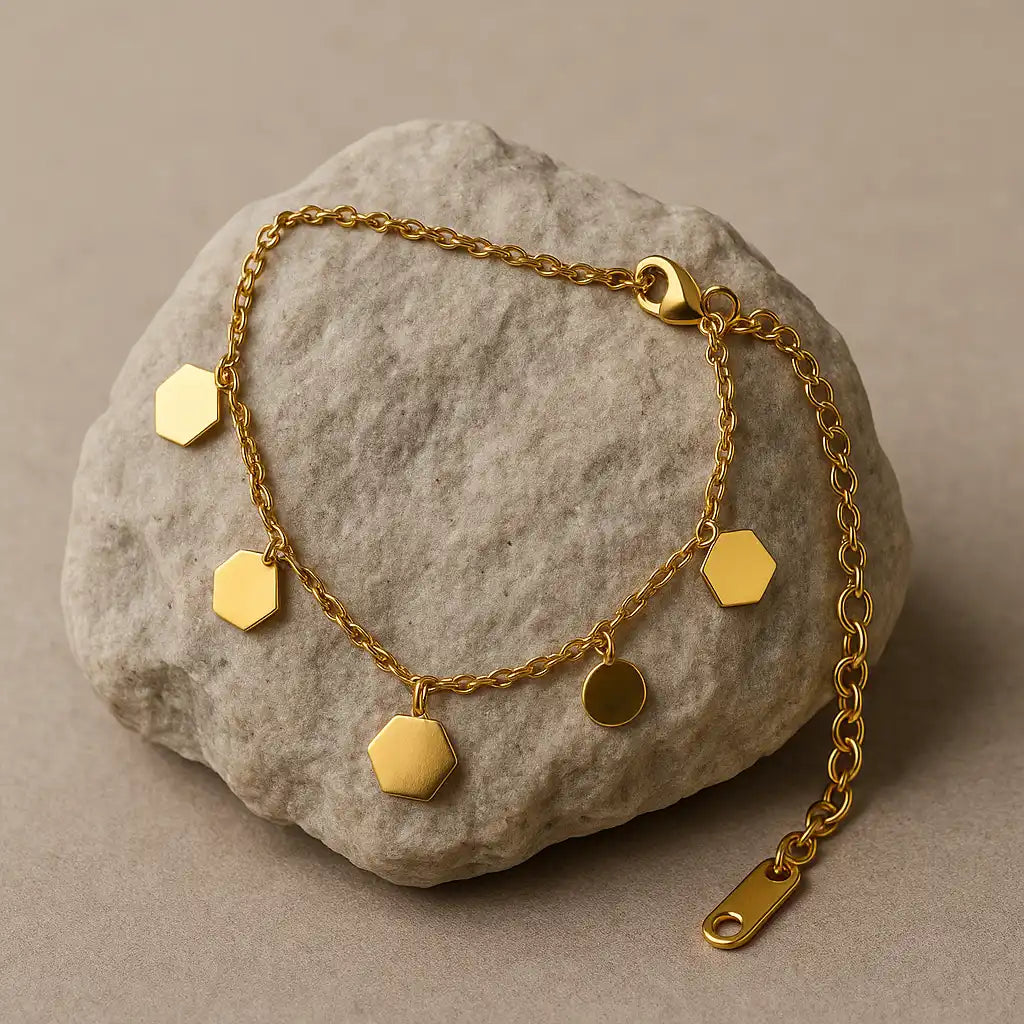 Gold bracelet with hexagonal charms on a stone surface