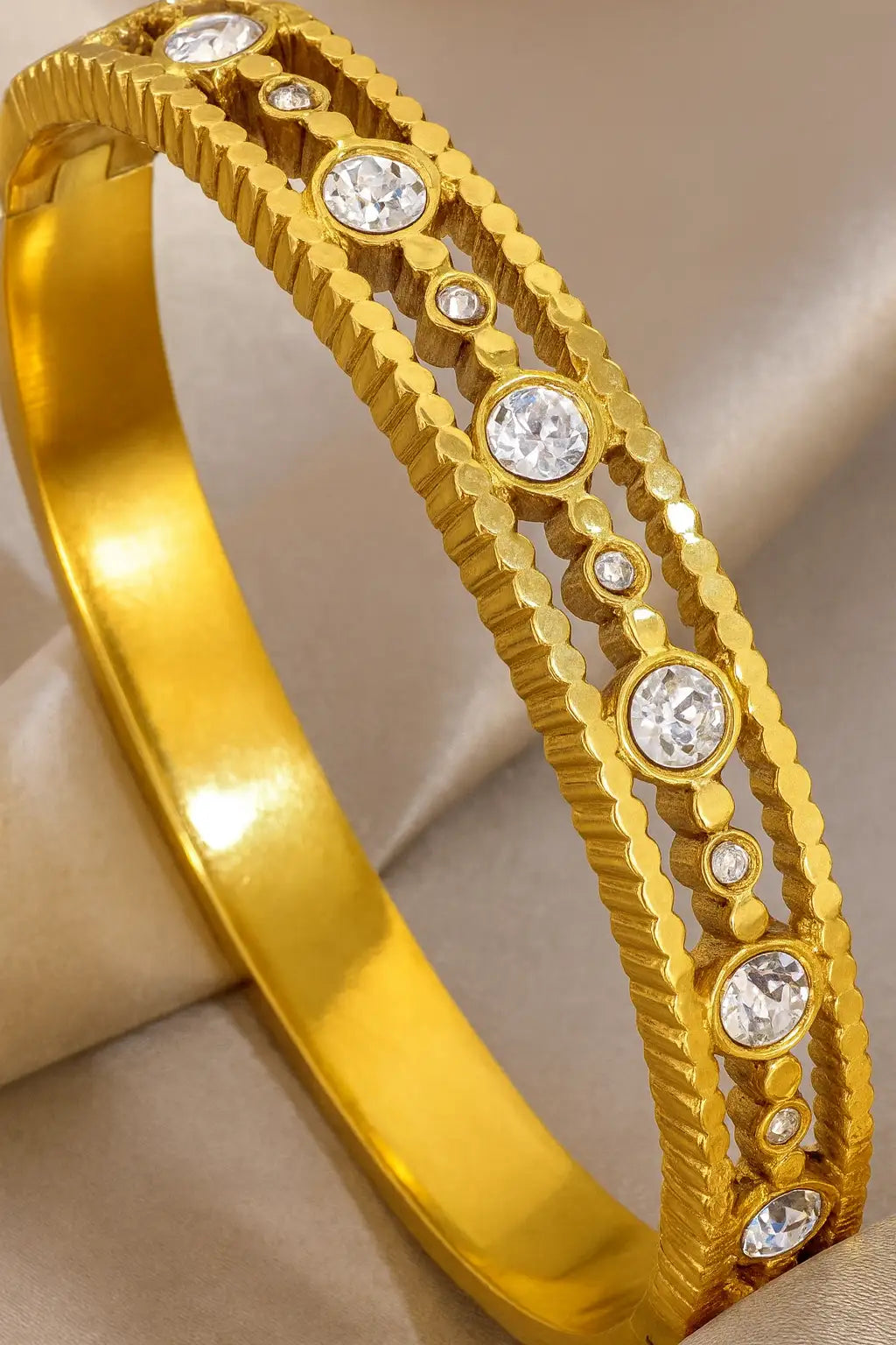 Gold bracelet with embedded crystals on a beige background