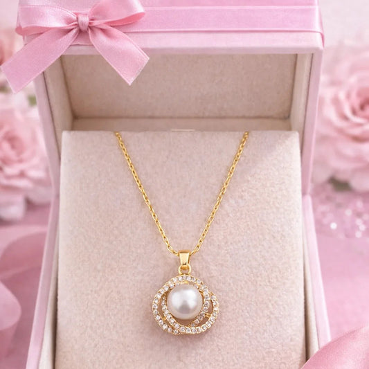 Gold necklace with a pearl pendant in a pink box with a bow