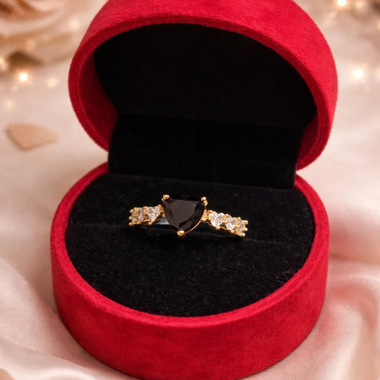 Red velvet jewelry box with a black gemstone ring on a soft background