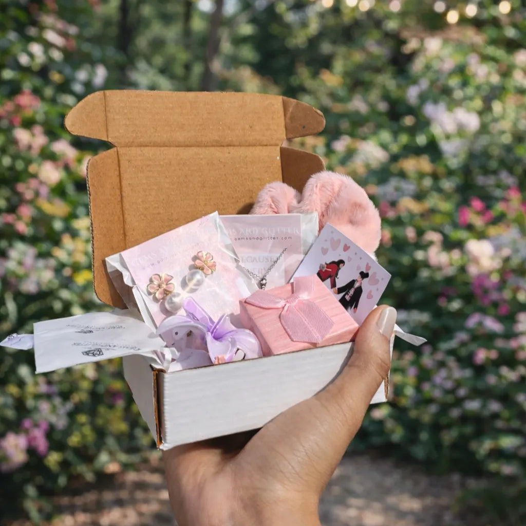Hand holding a small box with stationery items against a blurred garden background