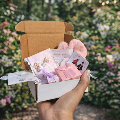 Hand holding a small box with stationery items against a blurred garden background
