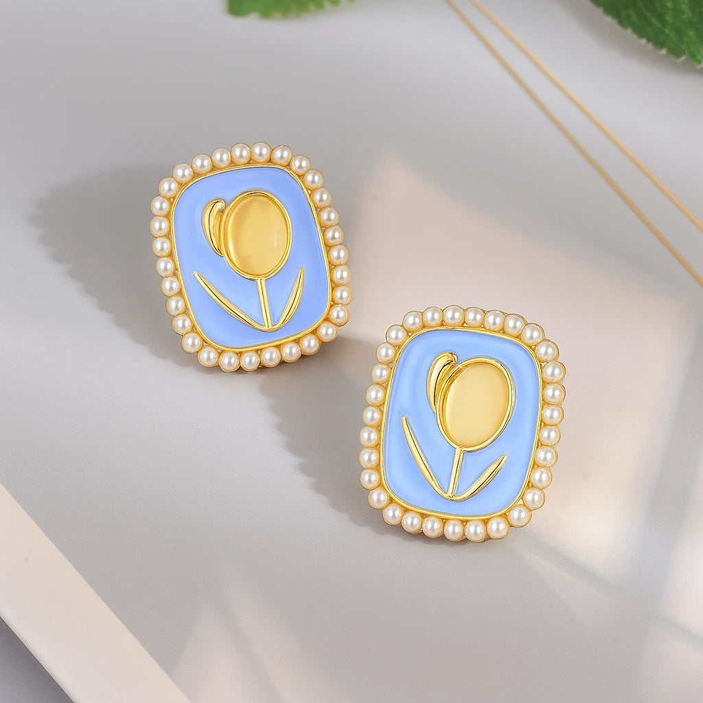 Pair of earrings with gold tulip design and pearl border on a light background