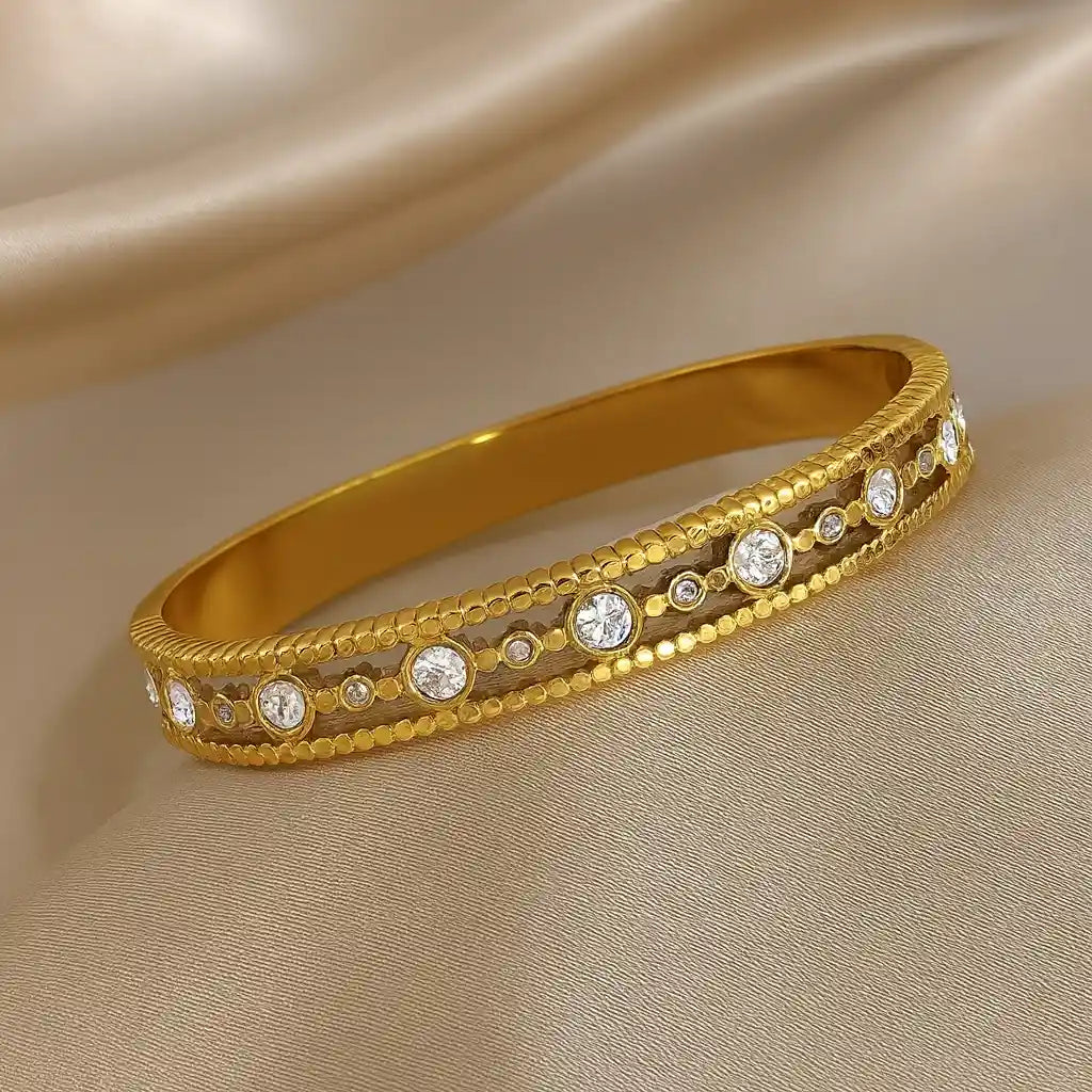 Gold bracelet with embedded diamonds on a beige fabric background