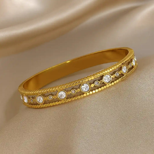 Gold bracelet with embedded diamonds on a beige fabric background