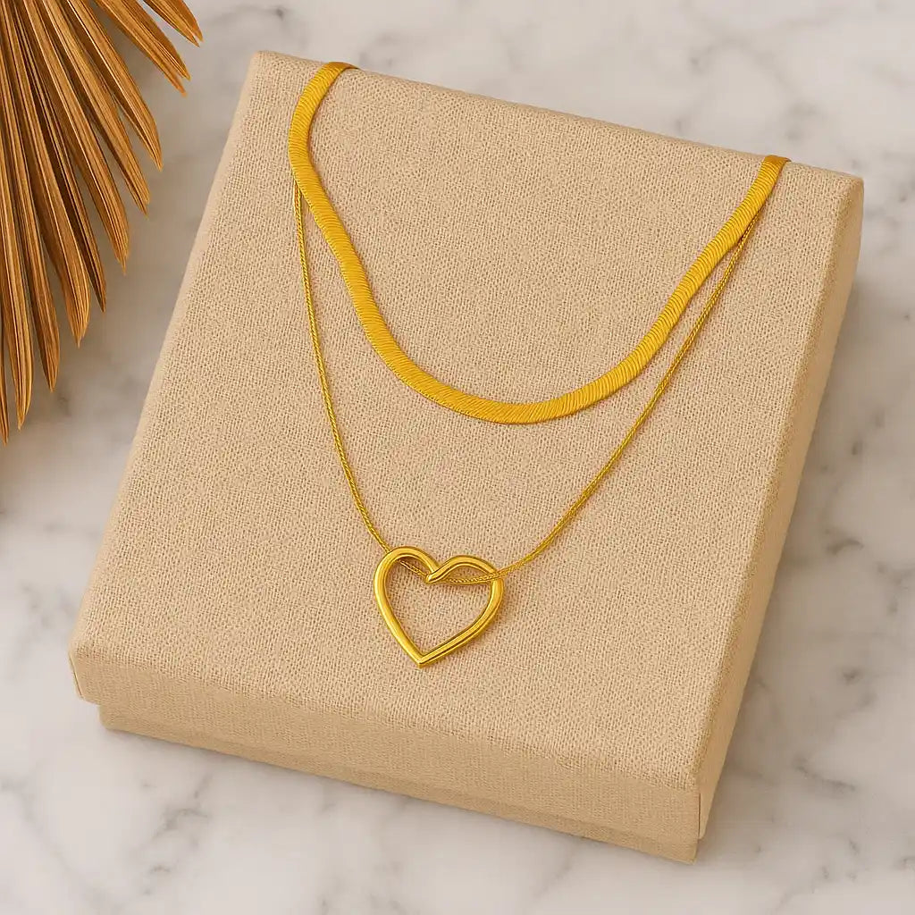 Gold necklace with a heart pendant on a beige jewelry box