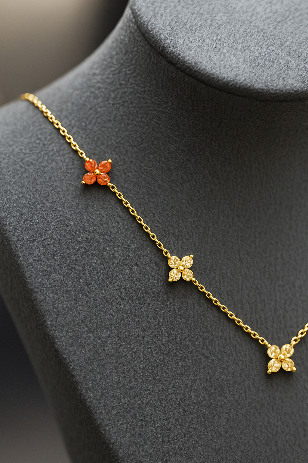 Gold necklace with floral pendants on a gray stand