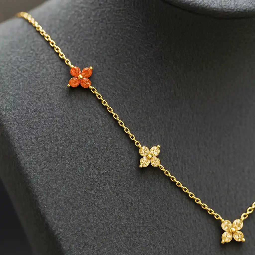 Gold necklace with floral pendants on a gray mannequin bust