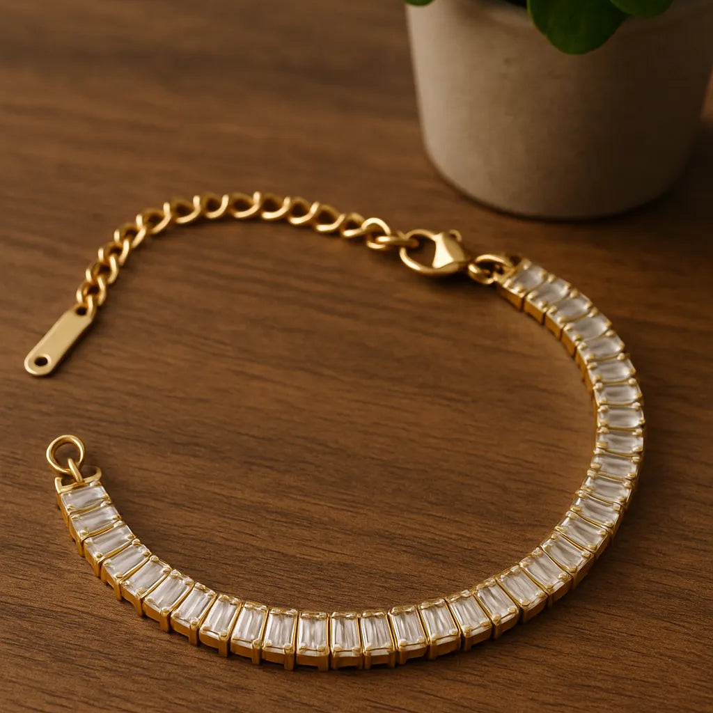 Gold bracelet with clear stones on a wooden surface next to a potted plant