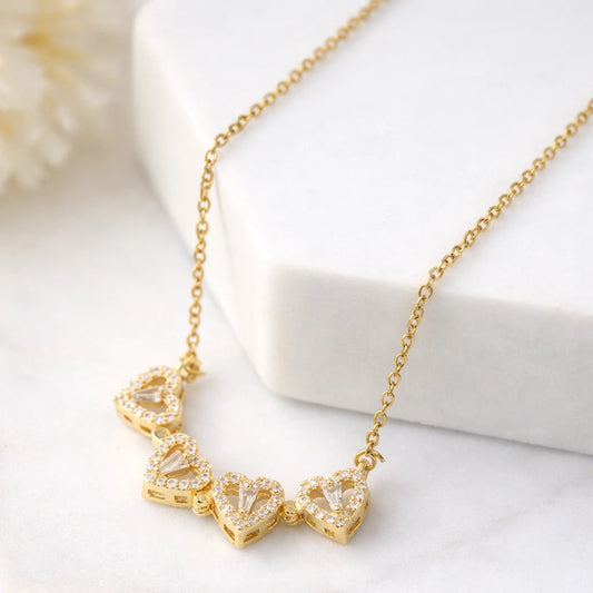 Gold necklace with heart-shaped pendants on a white surface