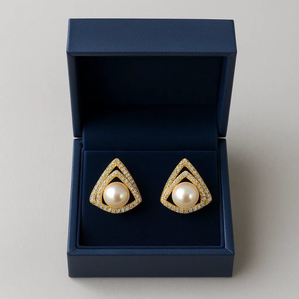 Pair of gold and pearl earrings in a blue box on a light gray background