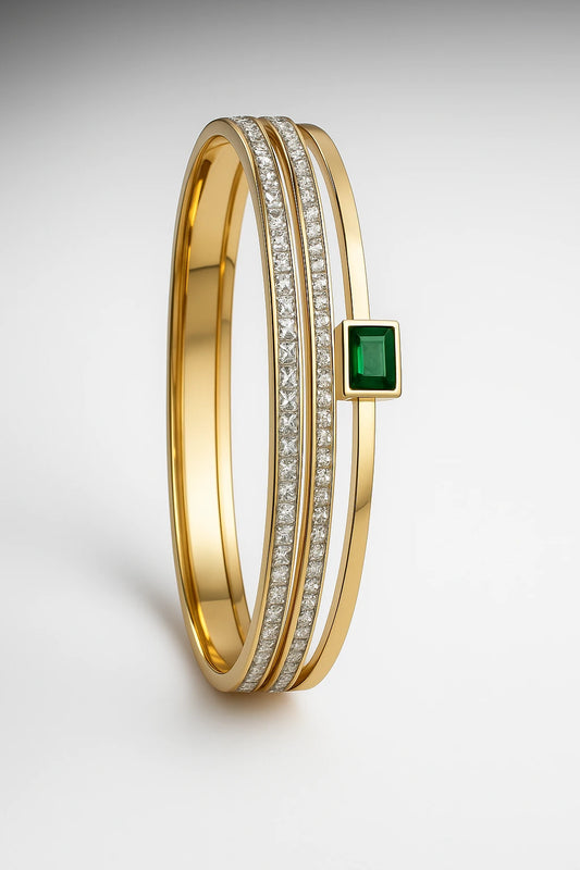 Gold bracelet with emerald and diamonds on a light gray background