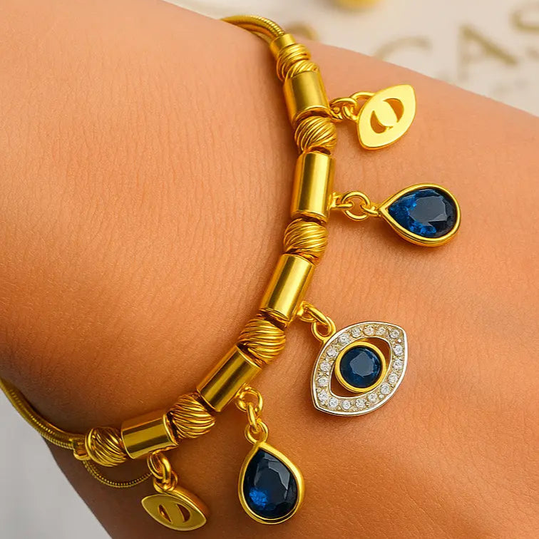 Gold bracelet with blue gemstones on a wrist against a light background