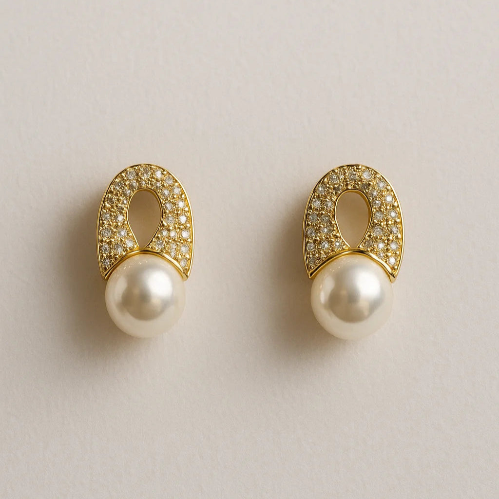 Pair of gold earrings with pearls on a light beige background