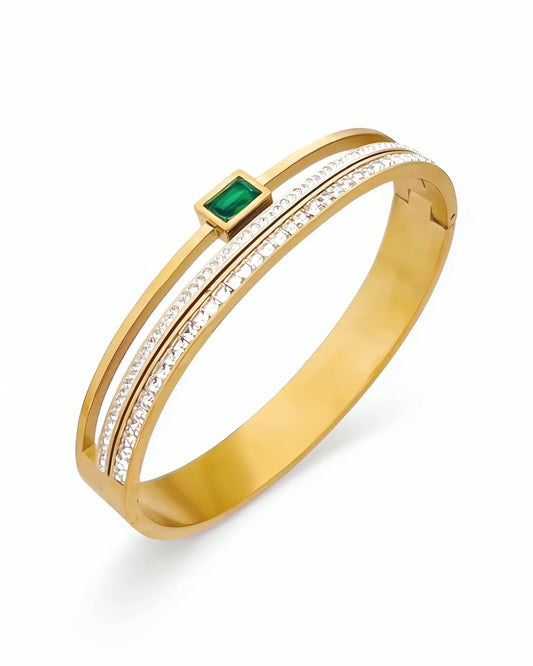 Gold bracelet with a green gemstone and clear stones on a white background