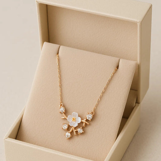 Gold necklace with a floral design in an open beige jewelry box on a beige background
