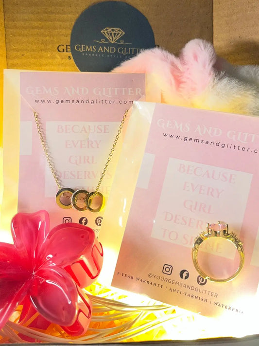 Necklace with heart pendants on a 'Gems and Glitter' card with a pink flower and yellow box in the background.