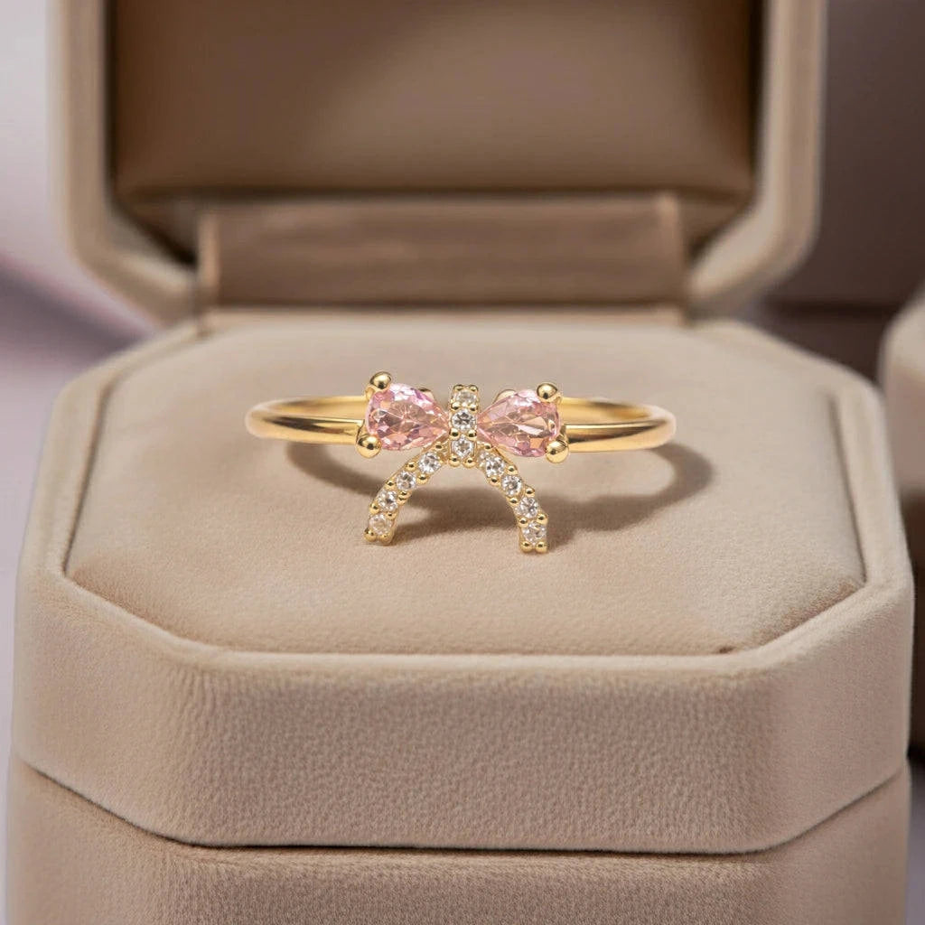 Gold ring with pink gemstones in a beige jewelry box