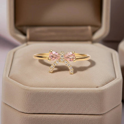 Gold ring with pink gemstones in a beige jewelry box