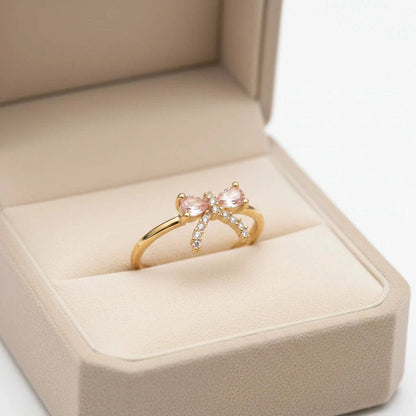 Gold ring with pink gemstones in a beige jewelry box