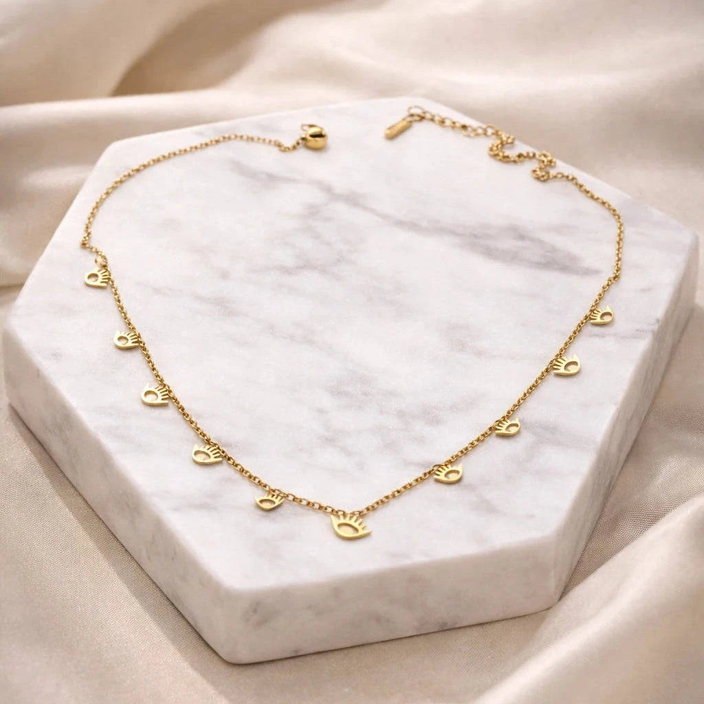 Gold necklace on a marble stand with a soft beige fabric background
