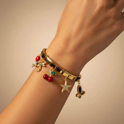 Gold bracelet with charms on a wrist against a beige background